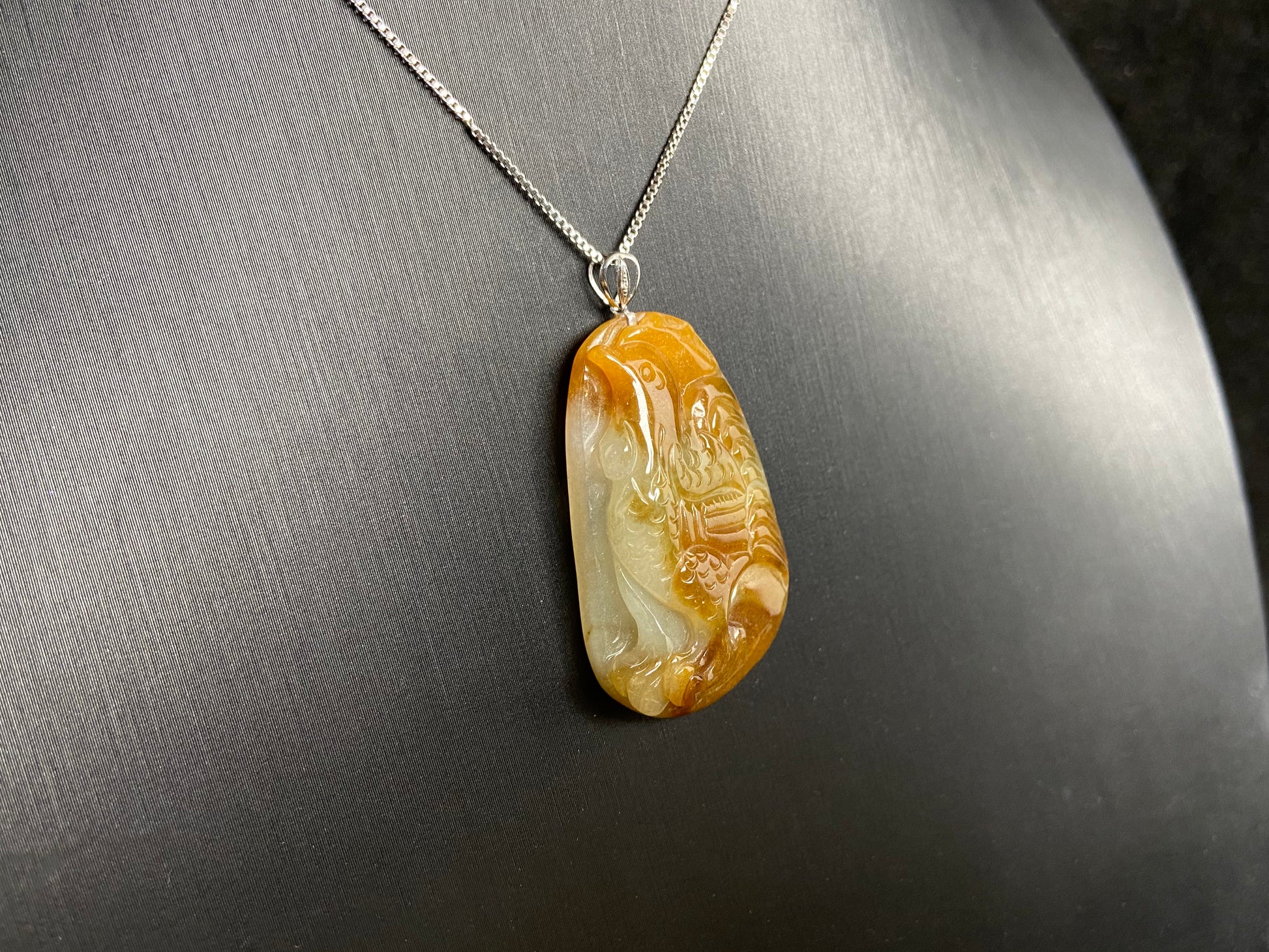 This jade pendant features a phoenix design in warm brown tones with subtle white accents, symbolizing nobility and good fortune.