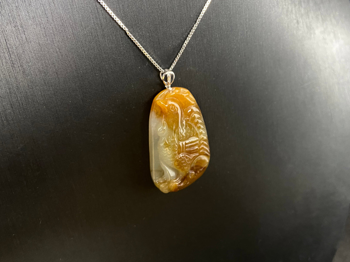This jade pendant features a phoenix design in warm brown tones with subtle white accents, symbolizing nobility and good fortune.