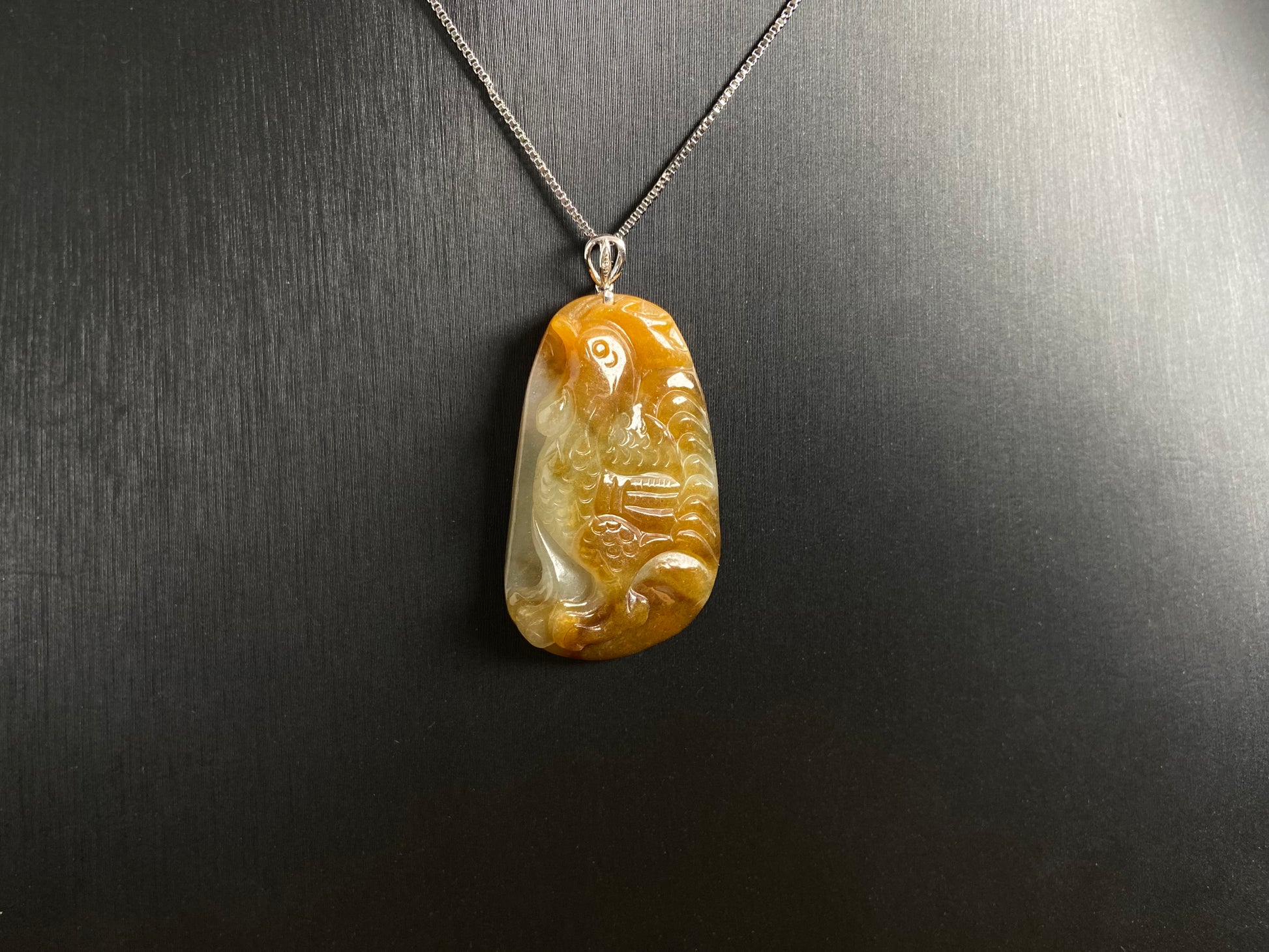 This jade pendant features a phoenix design in warm brown tones with subtle white accents, symbolizing nobility and good fortune.