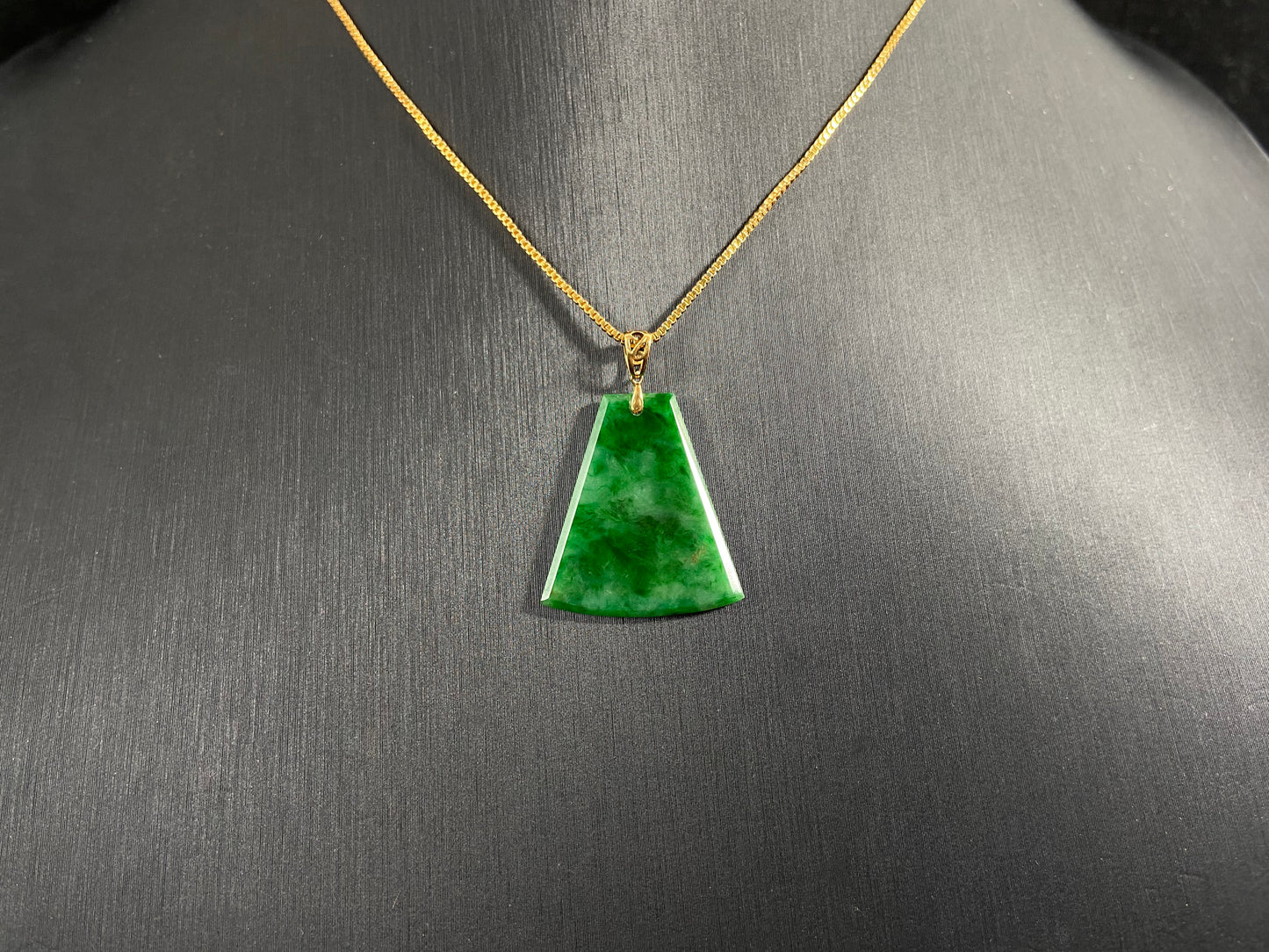 A light green jade plaque with darker green veining, featuring a gold plated 925 silver bail.