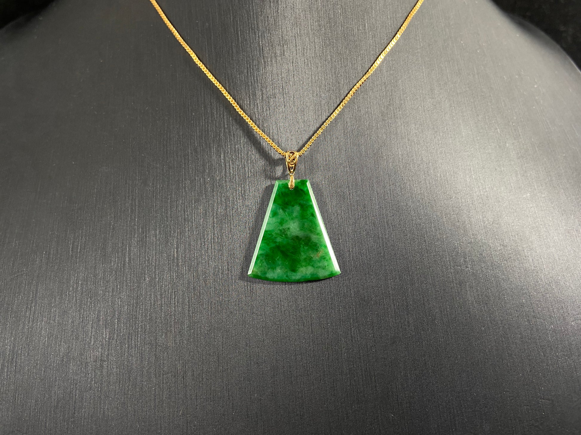 A light green jade plaque with darker green veining, featuring a gold plated 925 silver bail.