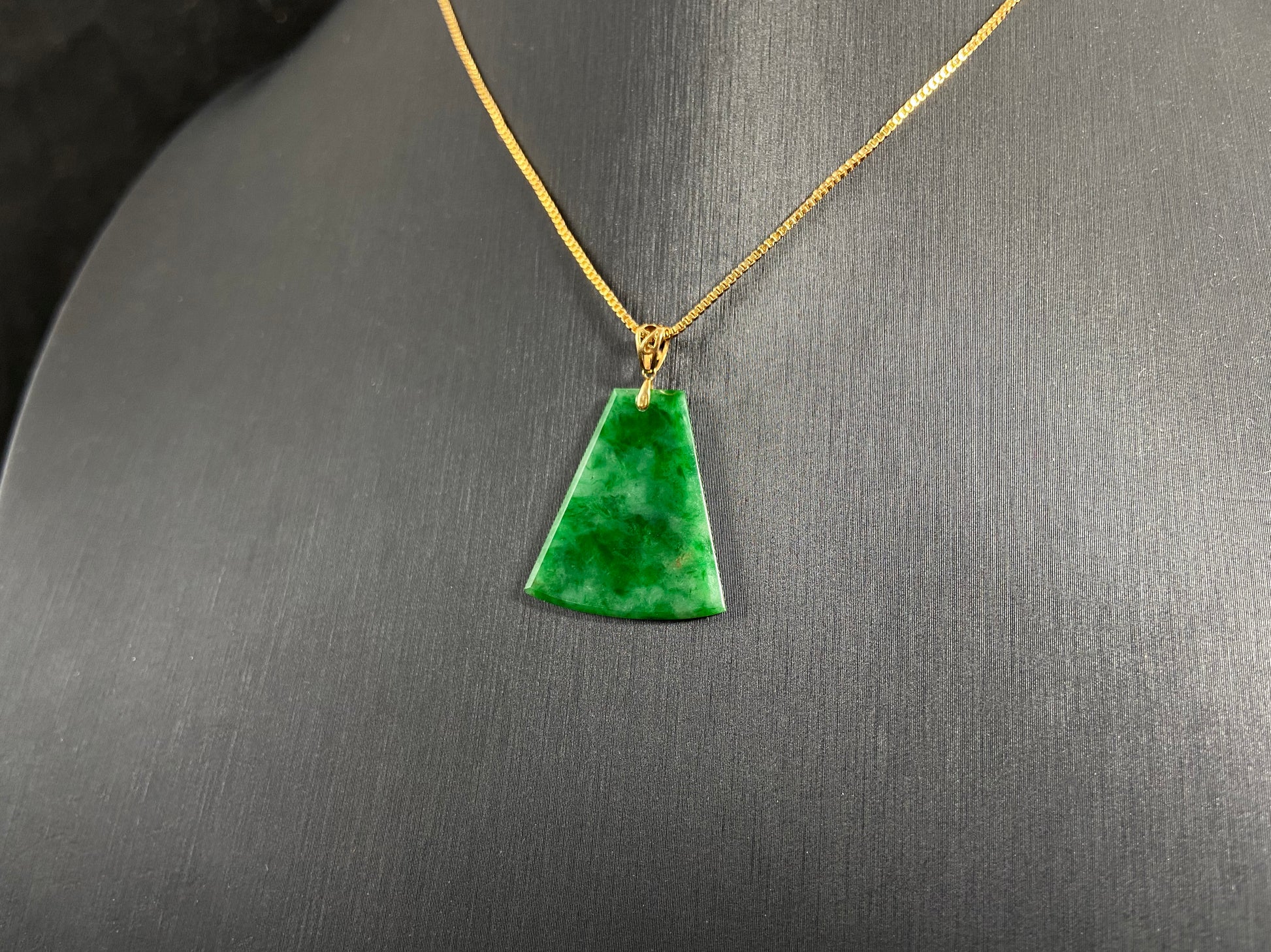 A light green jade plaque with darker green veining, featuring a gold plated 925 silver bail.