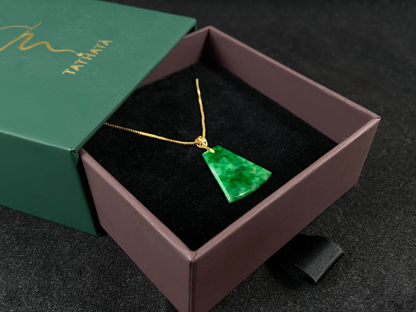 A light green jade plaque with darker green veining, featuring a gold plated 925 silver bail.