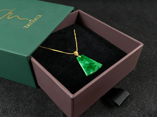 A light green jade plaque with darker green veining, featuring a gold plated 925 silver bail.