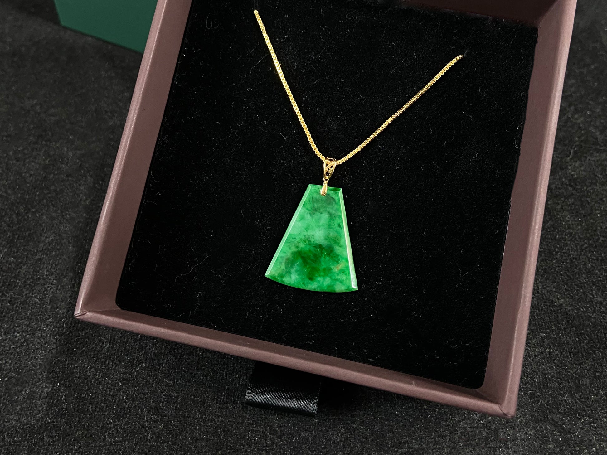 A light green jade plaque with darker green veining, featuring a gold plated 925 silver bail.