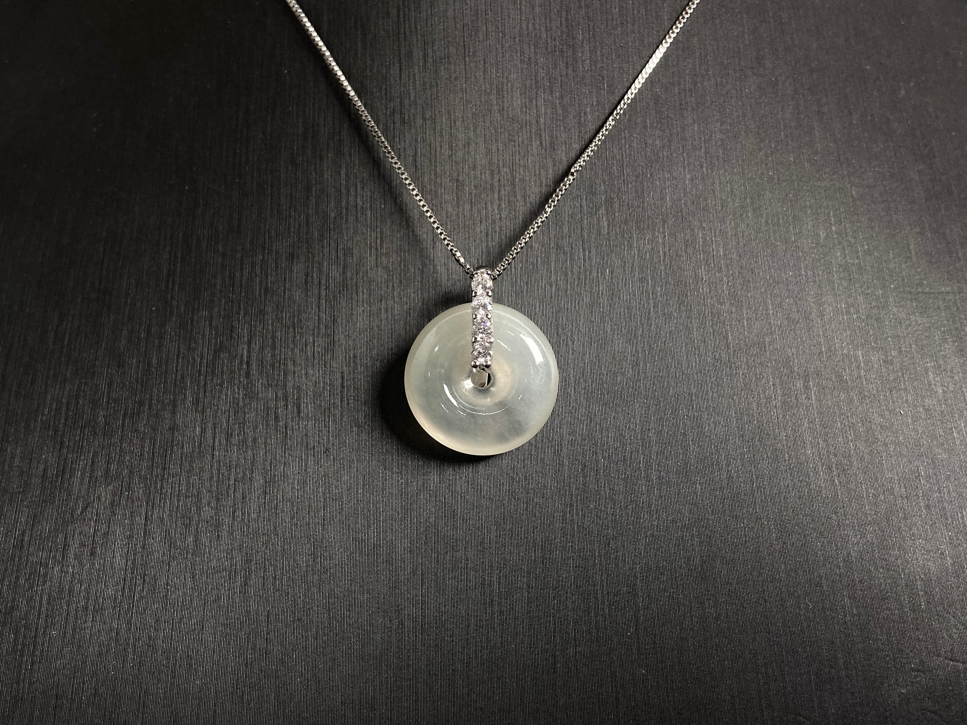 A serene icy clear jade circle pendant, embodying lifelong harmony and peace in its graceful form.