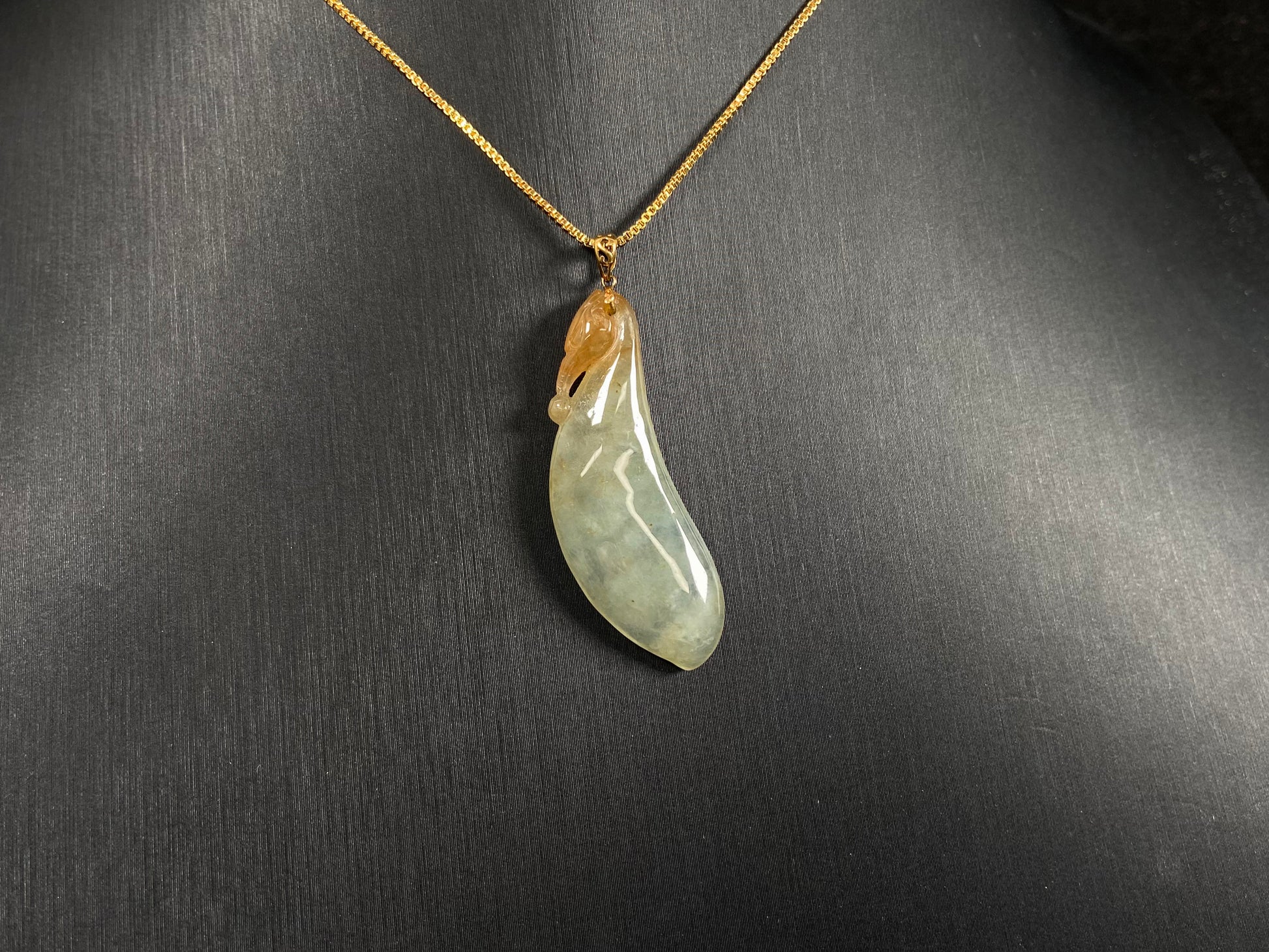 An icy jadeite "Fu Gua" pendant with gold speckles.