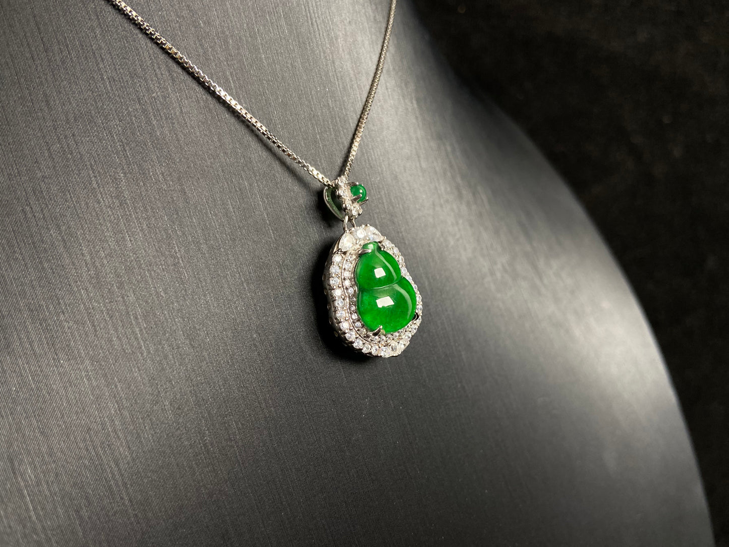 An imperial green jade gourd pendant, embraced by a diamond studded 925 silver frame.