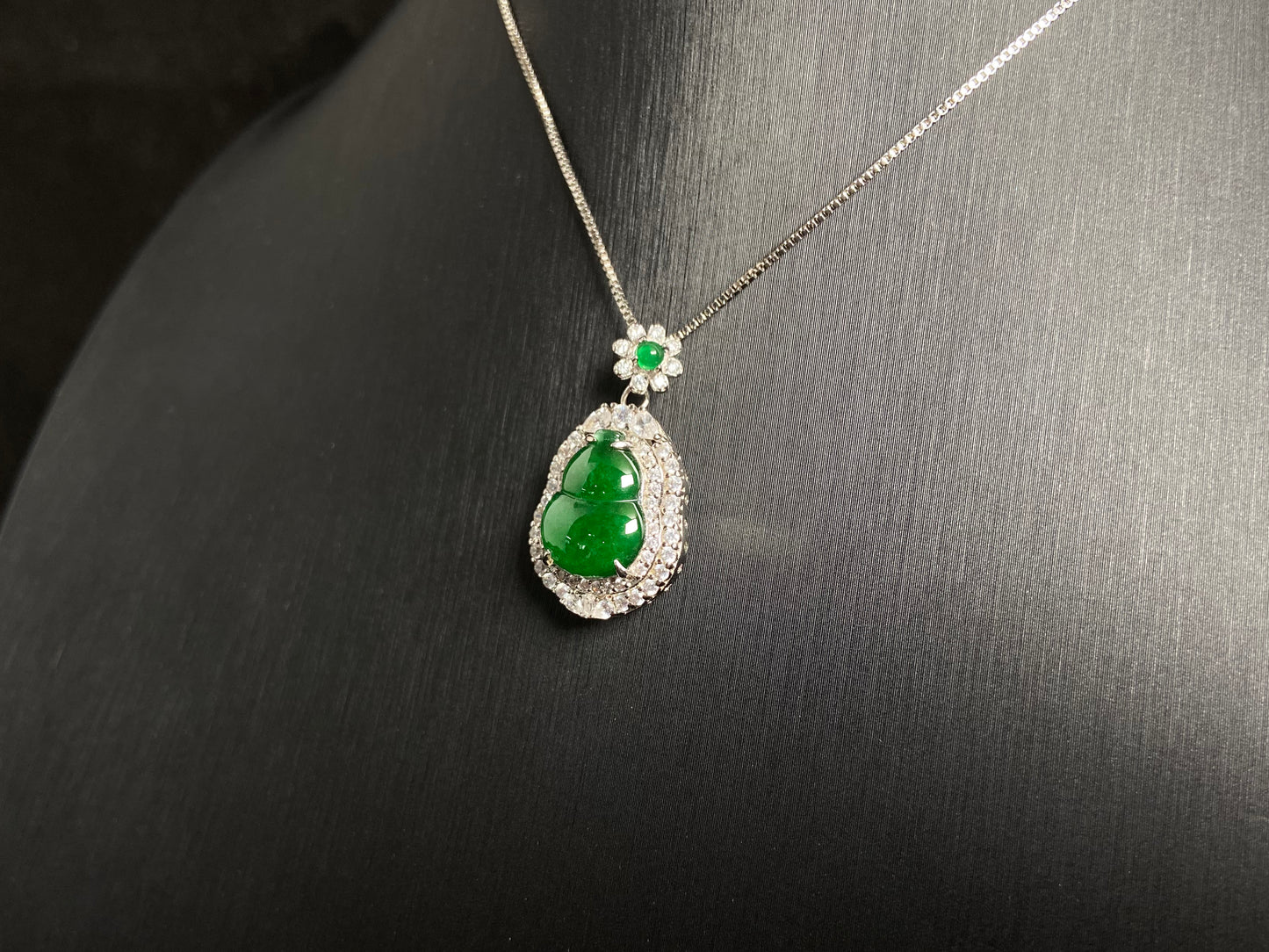 An imperial green jade gourd pendant, embraced by a diamond studded 925 silver frame.