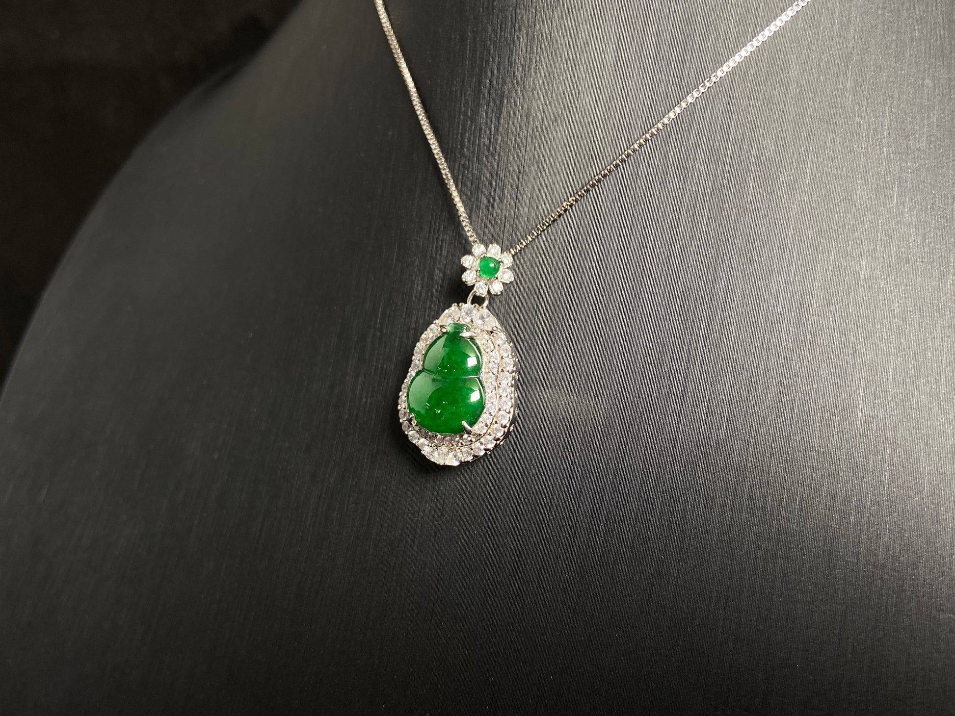 An imperial green jade gourd pendant, embraced by a diamond studded 925 silver frame.