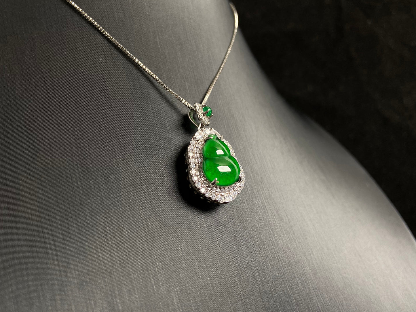 An imperial green jade gourd pendant, embraced by a diamond studded 925 silver frame.