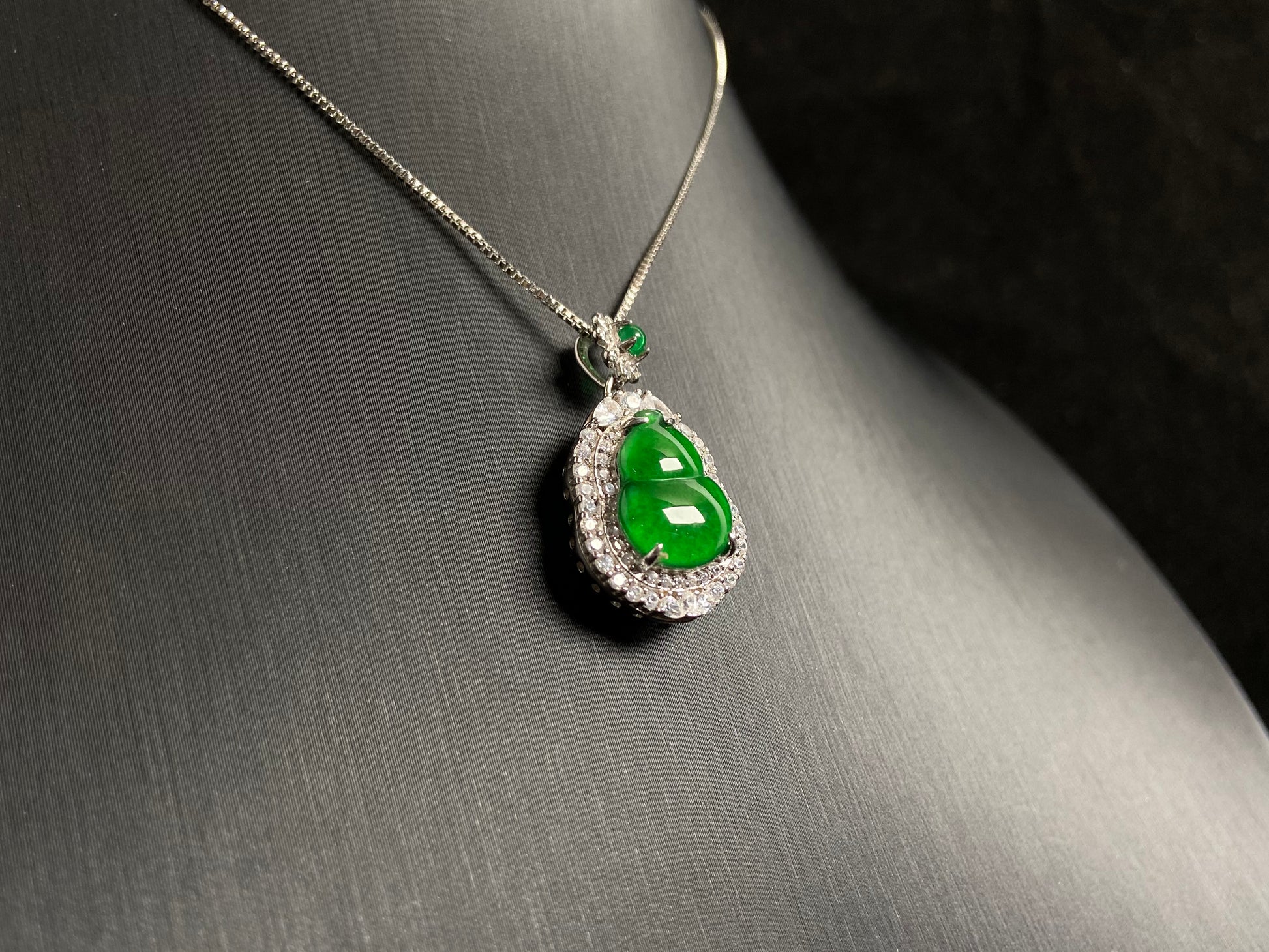 An imperial green jade gourd pendant, embraced by a diamond studded 925 silver frame.