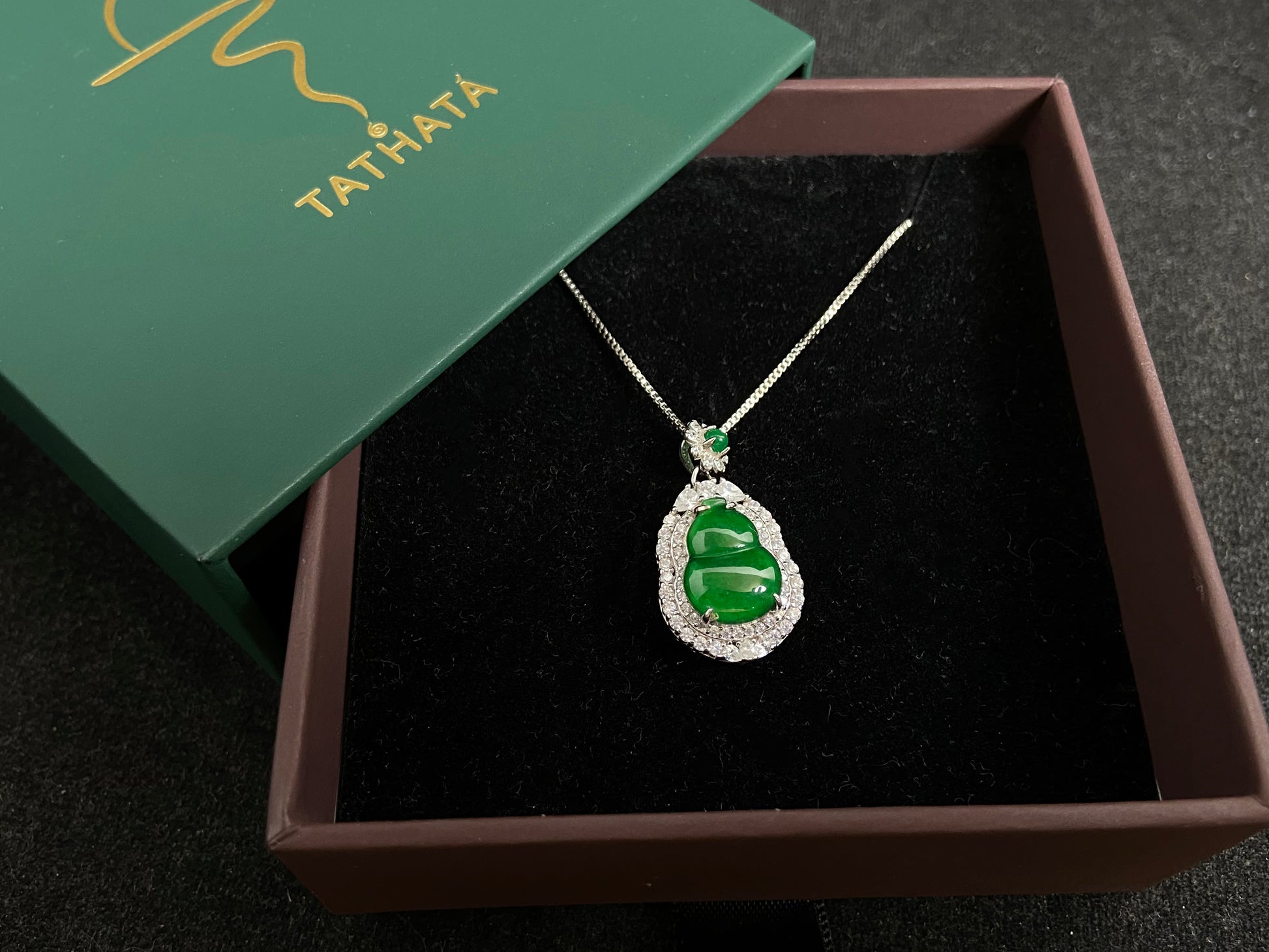 An imperial green jade gourd pendant, embraced by a diamond studded 925 silver frame.