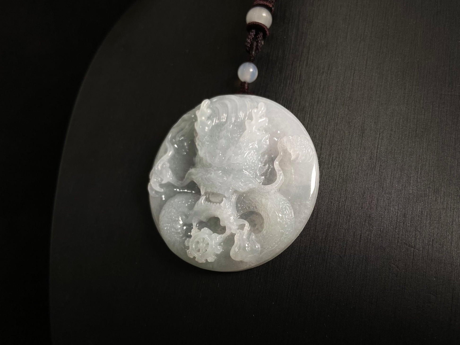 This exquisite pendant features a circular milky white jade disc intricately carved with a majestic dragon head design.