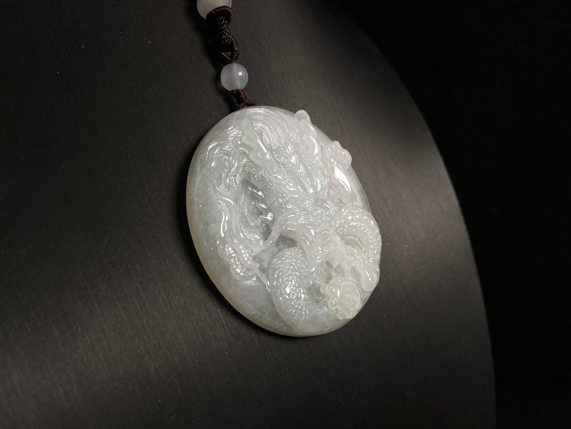 This exquisite pendant features a circular milky white jade disc intricately carved with a majestic dragon head design.