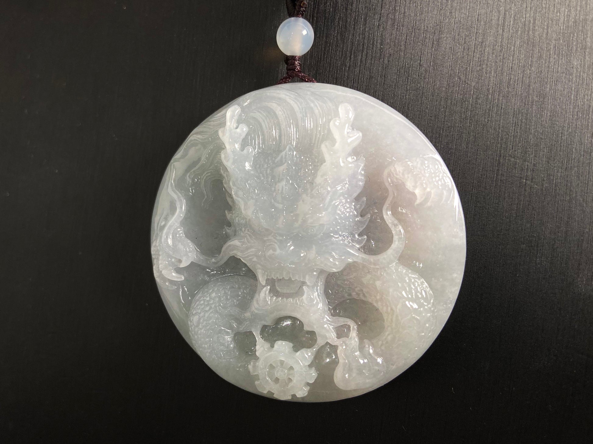 This exquisite pendant features a circular milky white jade disc intricately carved with a majestic dragon head design.
