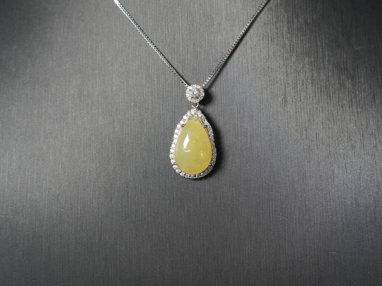 A pale yellow teardrop jadeite pendant.