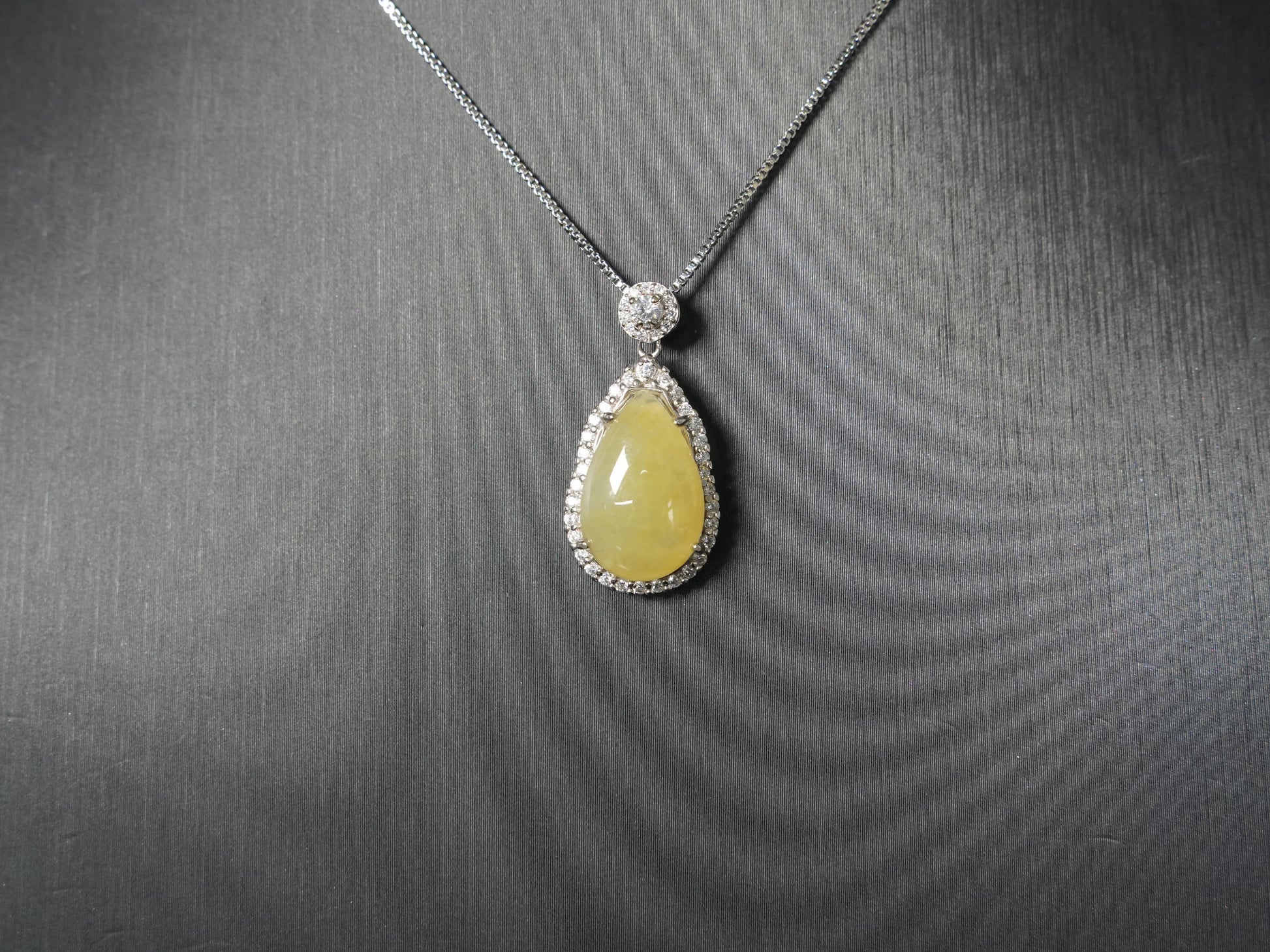 A pale yellow teardrop jadeite pendant.