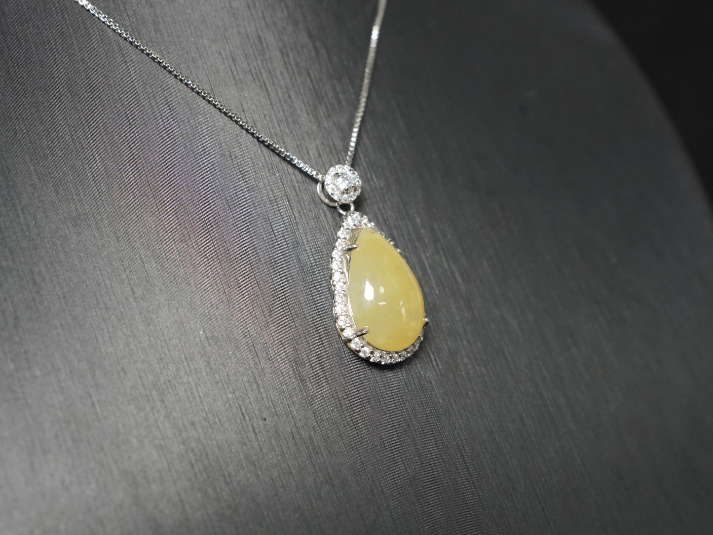 A pale yellow teardrop jadeite pendant.