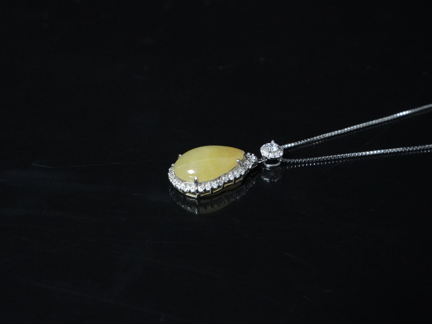 A pale yellow teardrop jadeite pendant.