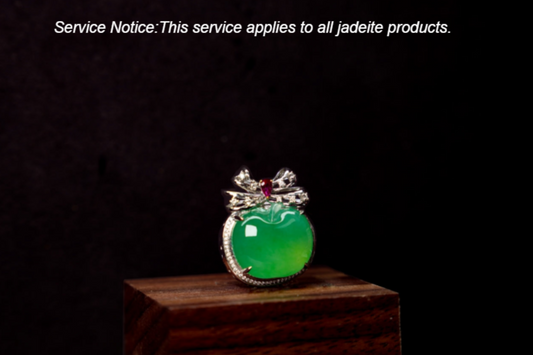 An imperial green jade apple pendant topped with a bow, featuring a rose colored gem at its center.