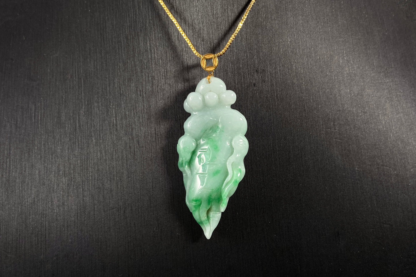 A white based ginseng shaped jade pendant with green accents flowing across its surface.