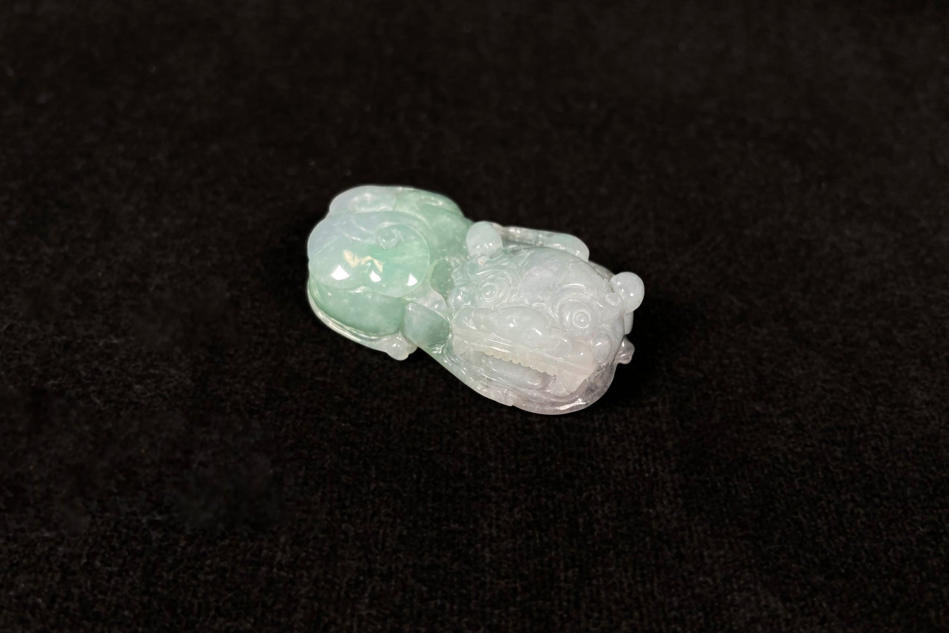 A Pi Xiu jadeite carving with a light green lower body and creamy white head.
