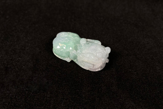 A Pi Xiu jadeite carving with a light green lower body and creamy white head.