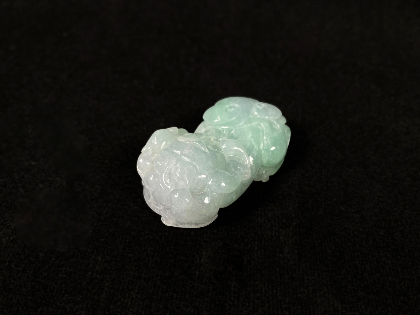A Pi Xiu jadeite carving with a light green lower body and creamy white head.