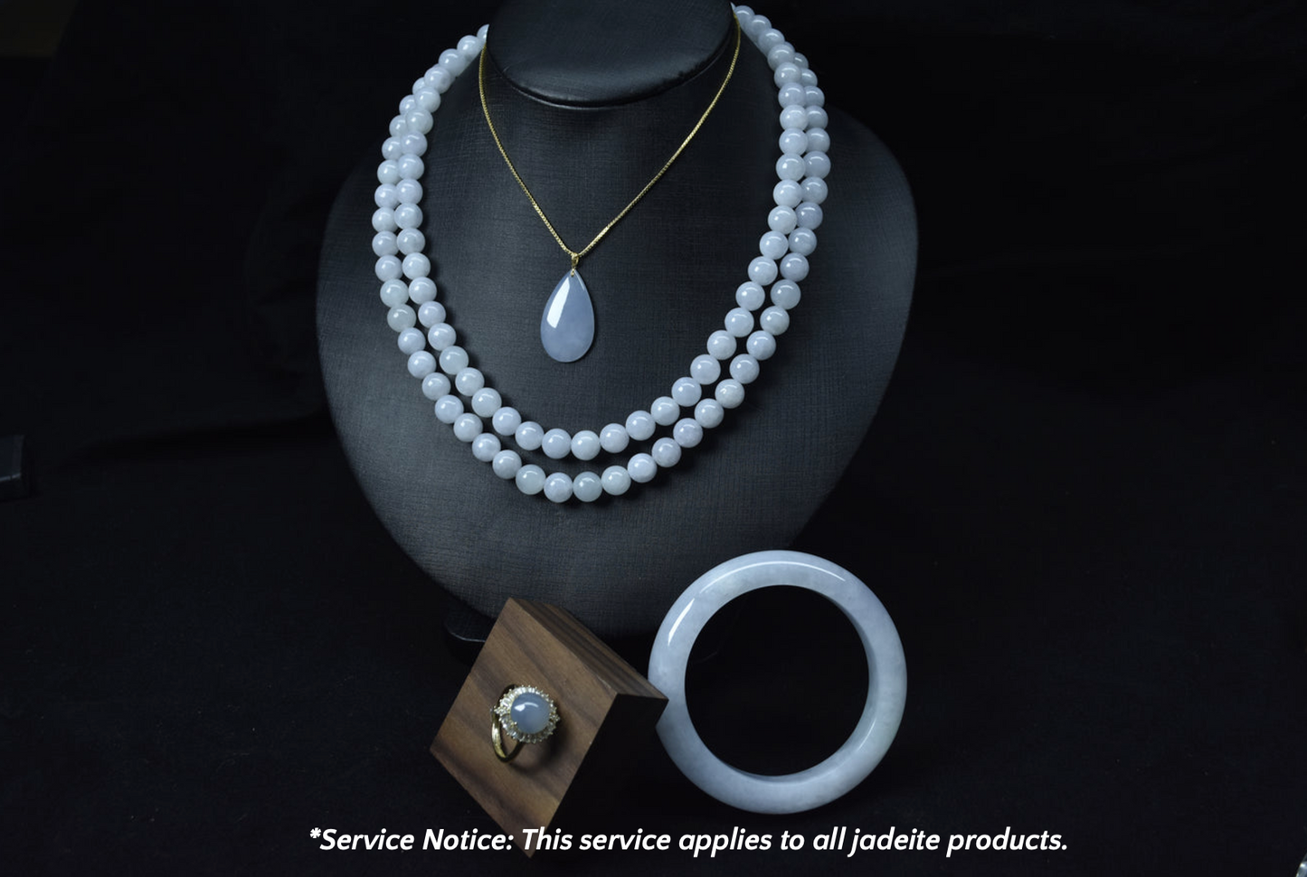 Jade necklace and bracelet on a black stand with a service notice at the bottom.