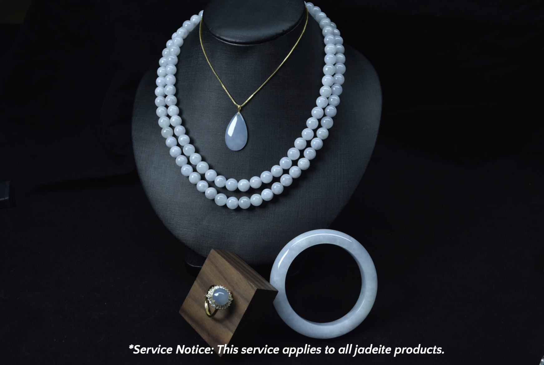 Jade necklace and bracelet on a black stand with a service notice at the bottom.