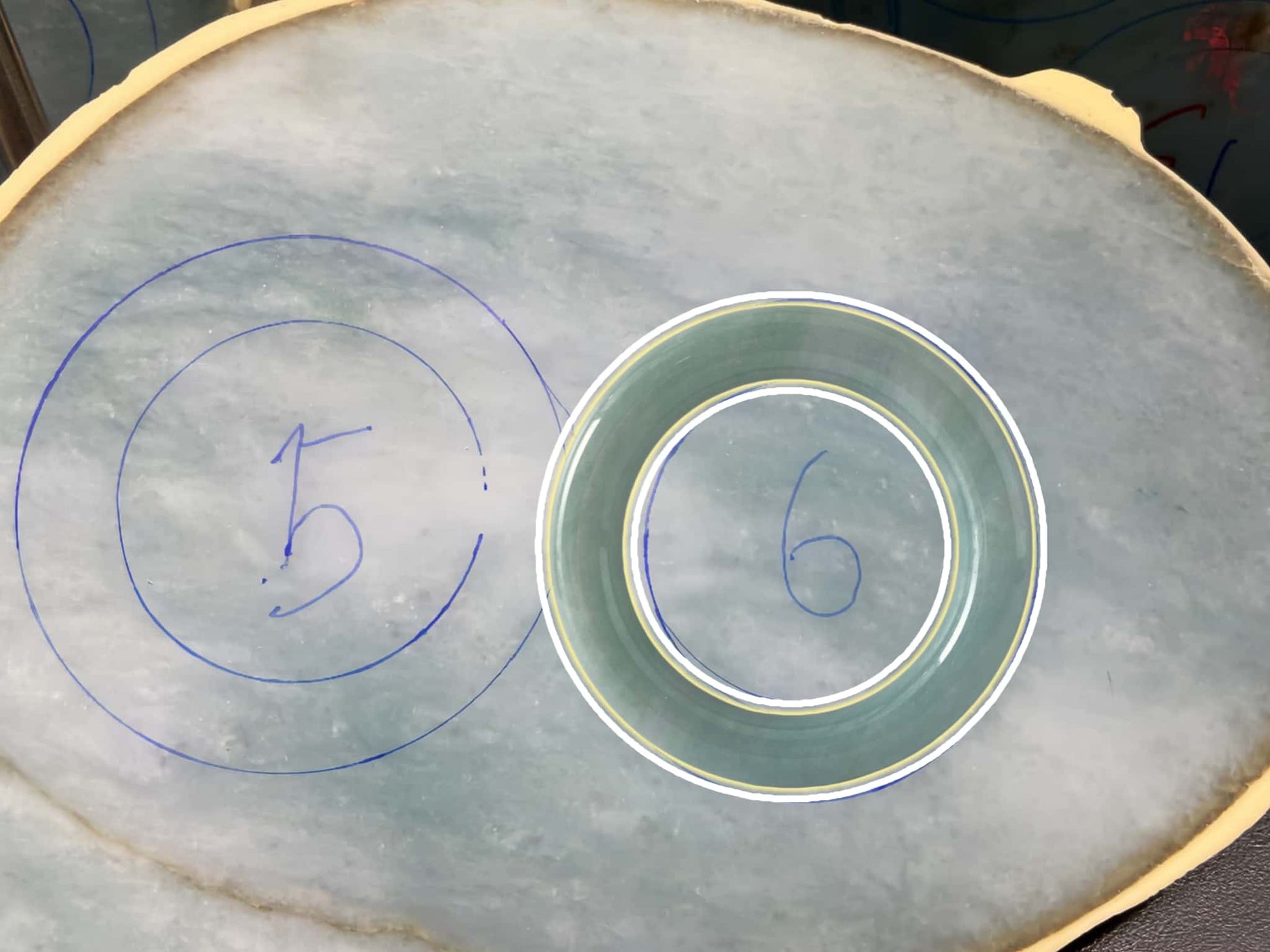 Circular patterns with numbers drawn on a textured surface. Multi-purpose Carving of Jadeite Rough Stones & Custom Bangle Services