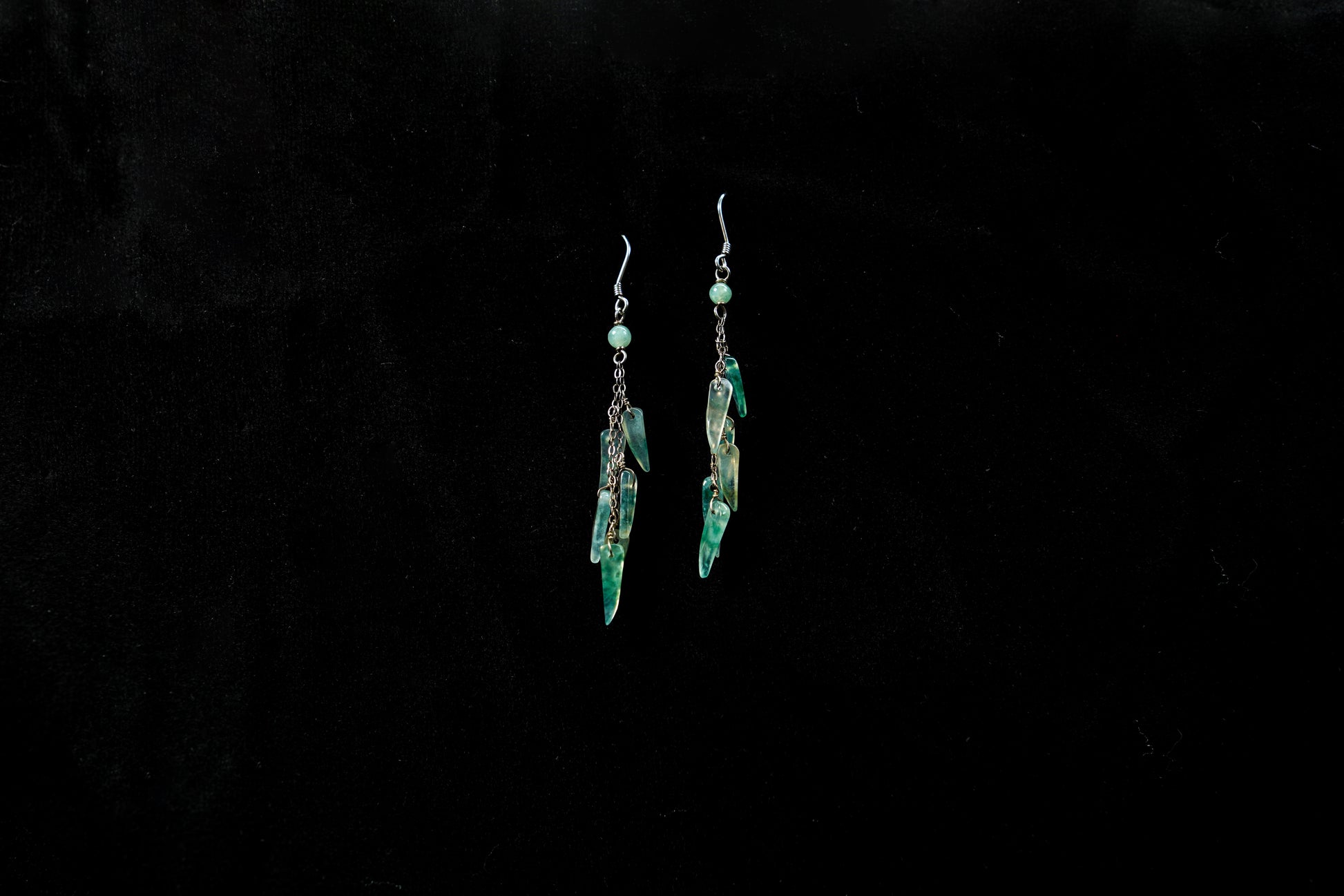 Pair of green earrings on a black background