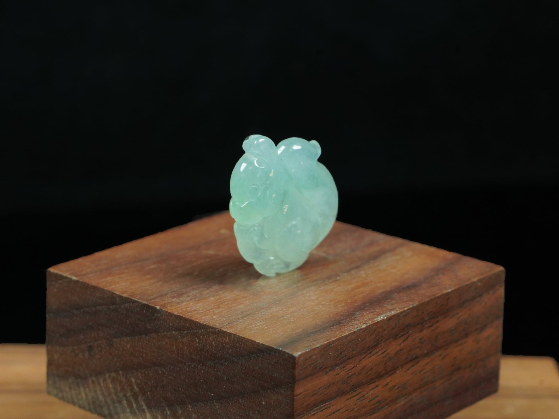 This jadeite carving features a lifelike three-dimensional squirrel rendered in a soft, luminous green with a pale white base.