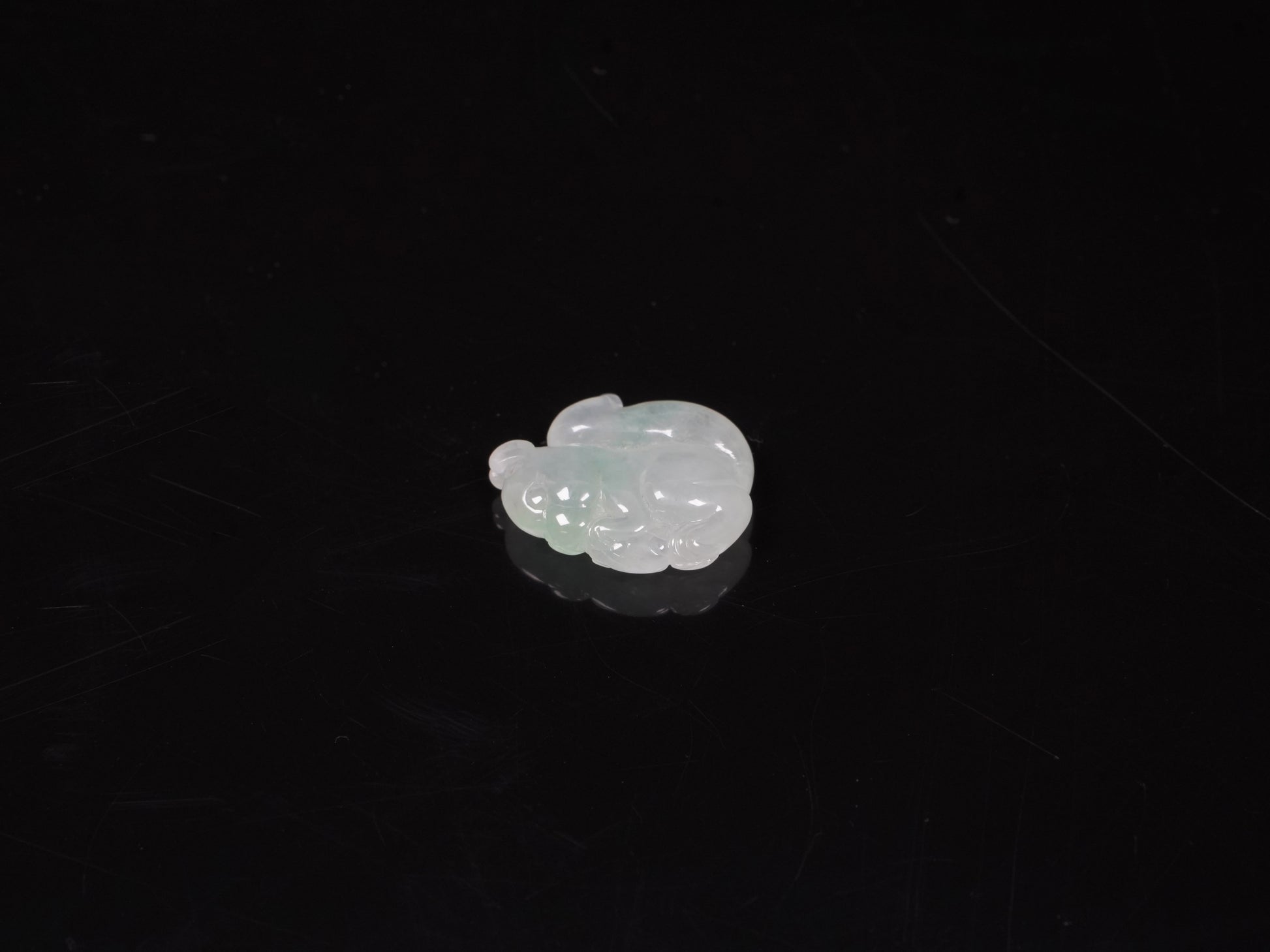 This jadeite carving features a lifelike three-dimensional squirrel rendered in a soft, luminous green with a pale white base.