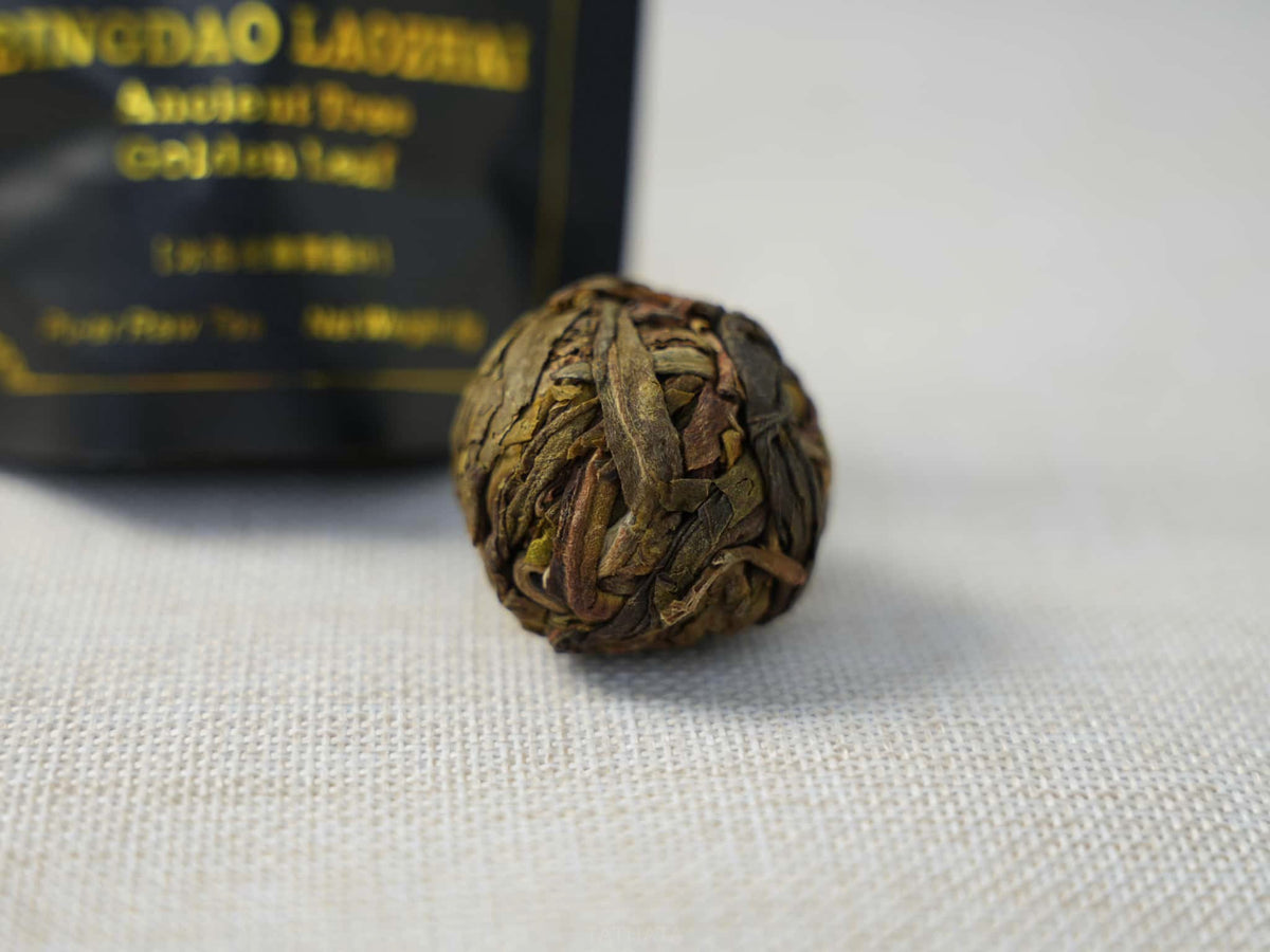 Close-up of "Golden Leaf" raw Pu-erh tea from ancient trees in Bingdao Laozhai: hand-rolled into a ball, revealing the strands of the dry tea leaves.