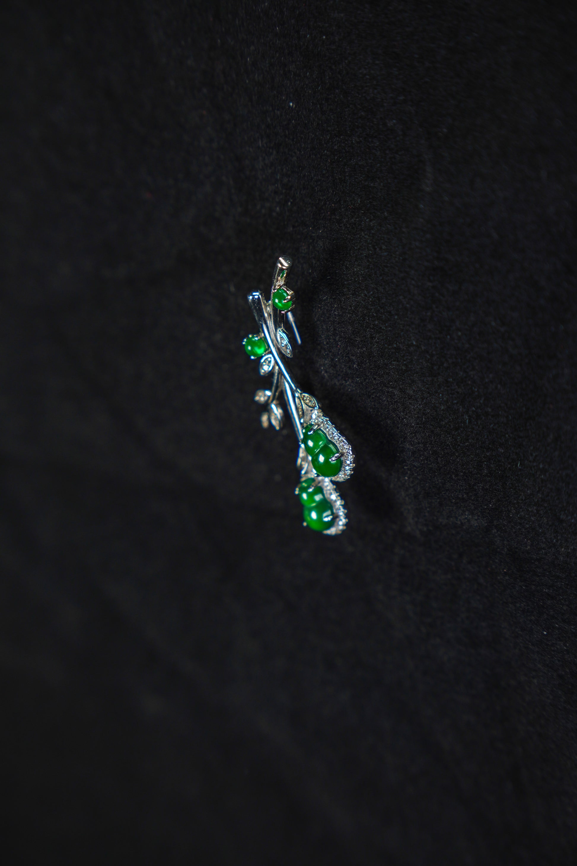 Silver pendant with green gemstones on a black background