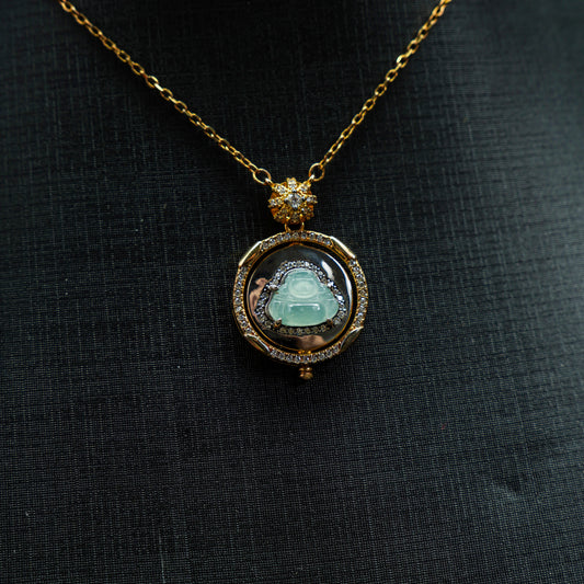 Gold necklace with a pendant featuring a green gemstone on a black fabric background