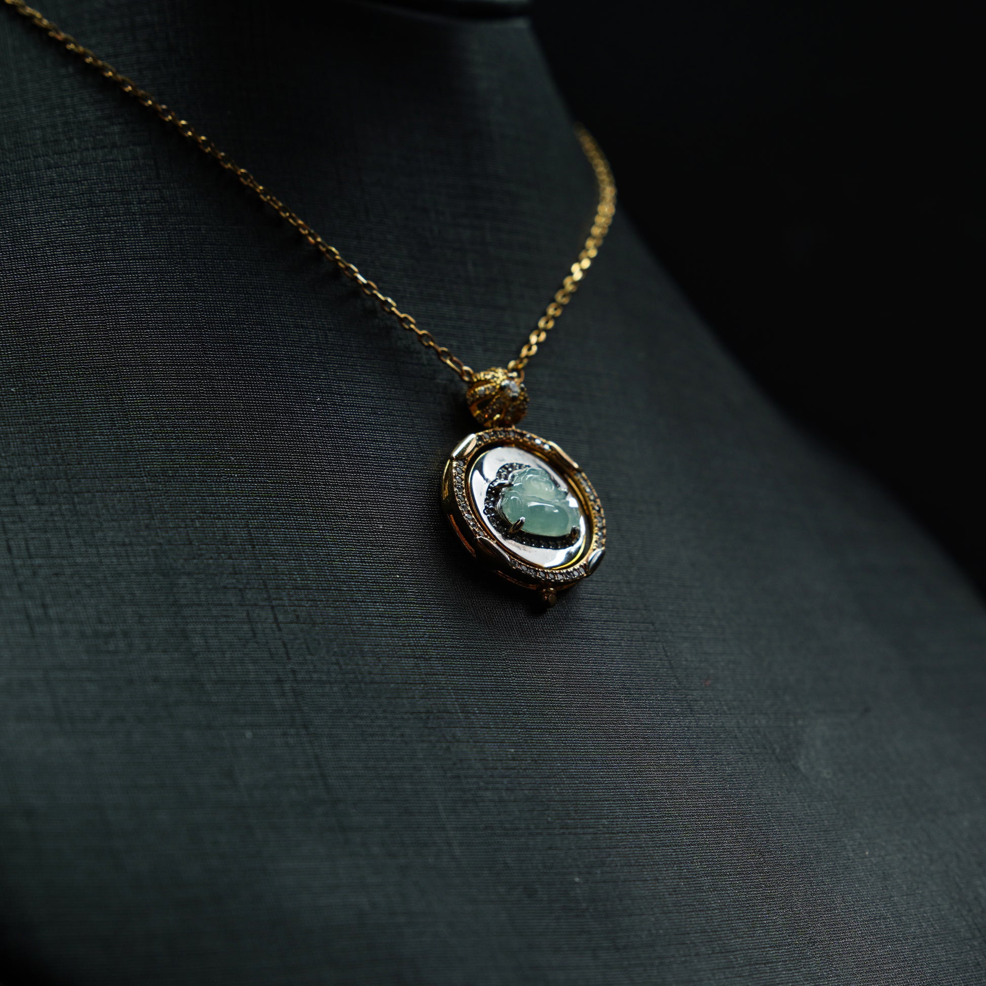 Necklace with a pendant featuring a green gemstone on a dark fabric background