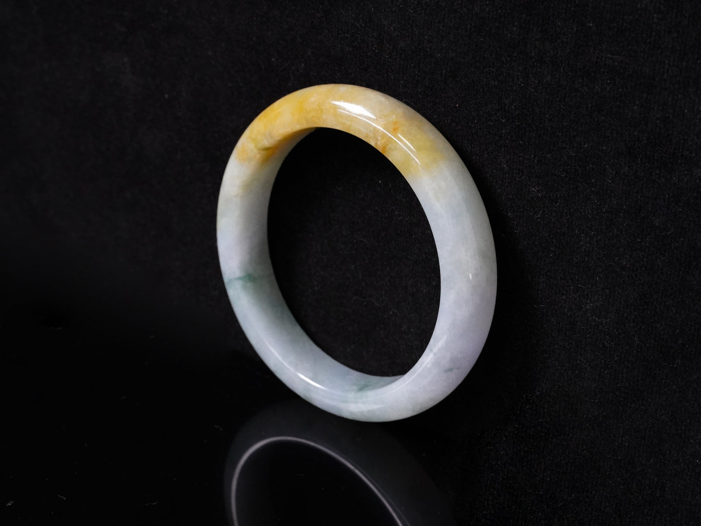 This jadeite bangle has a white base with floating green and honey-yellow hues.