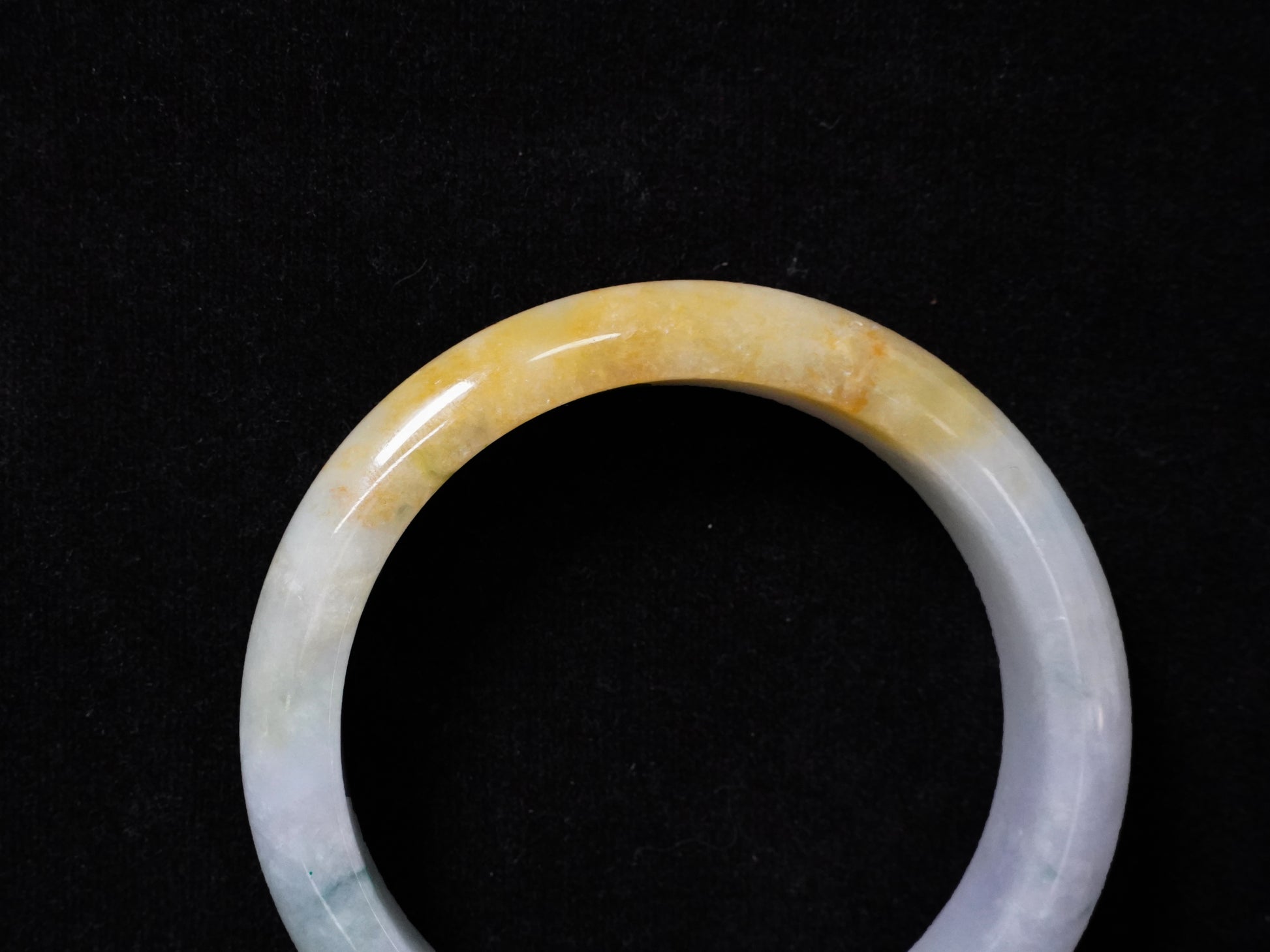 This jadeite bangle has a white base with floating green and honey-yellow hues.
