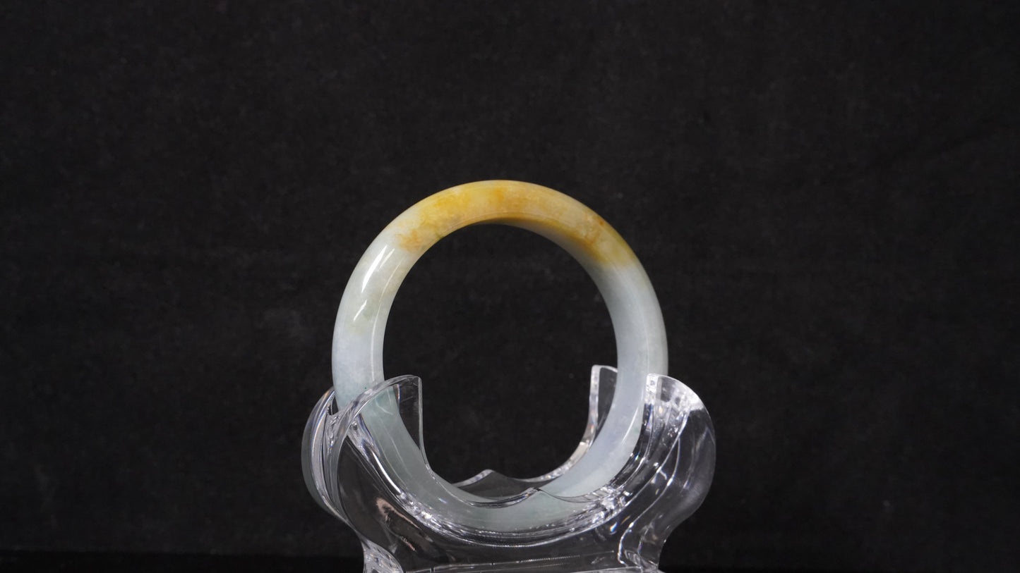 This jadeite bangle has a white base with floating green and honey-yellow hues.