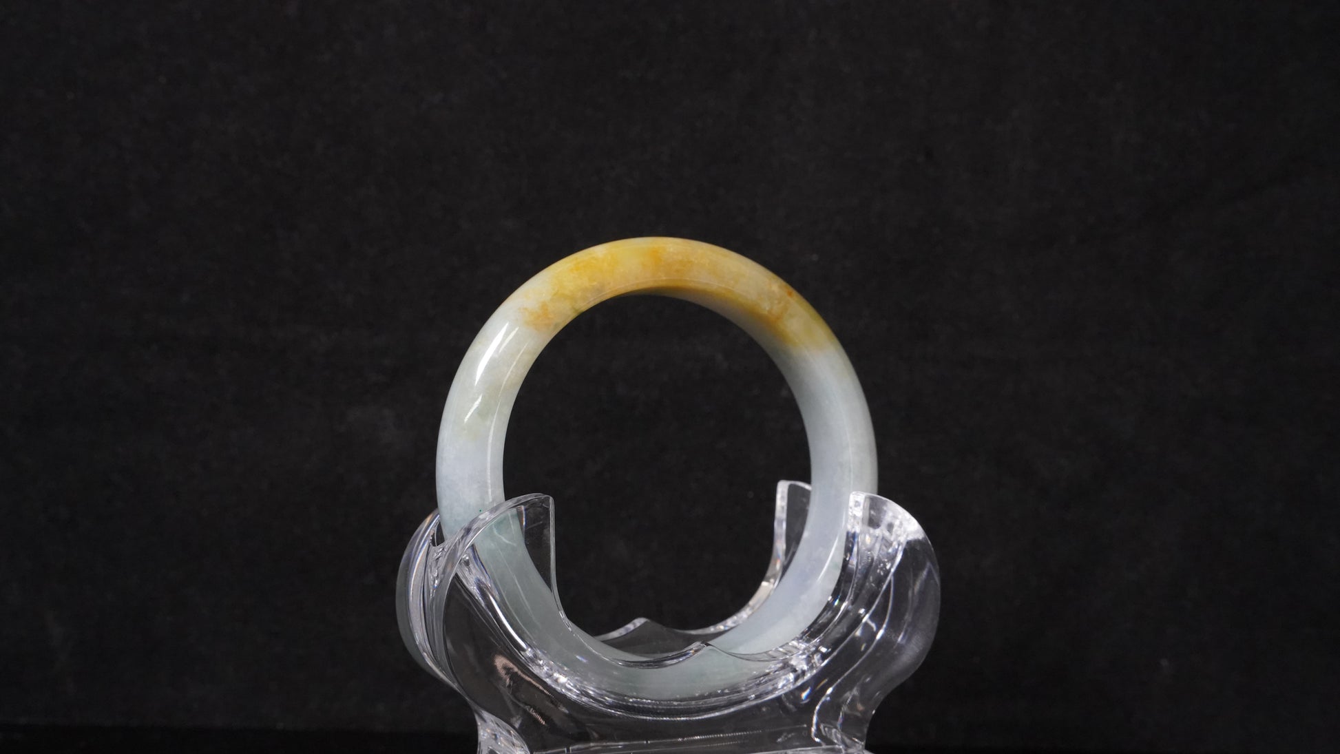 This jadeite bangle has a white base with floating green and honey-yellow hues.