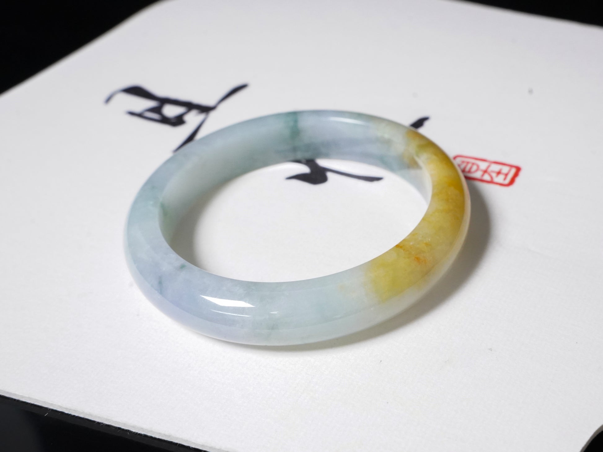 This jadeite bangle has a white base with floating green and honey-yellow hues.