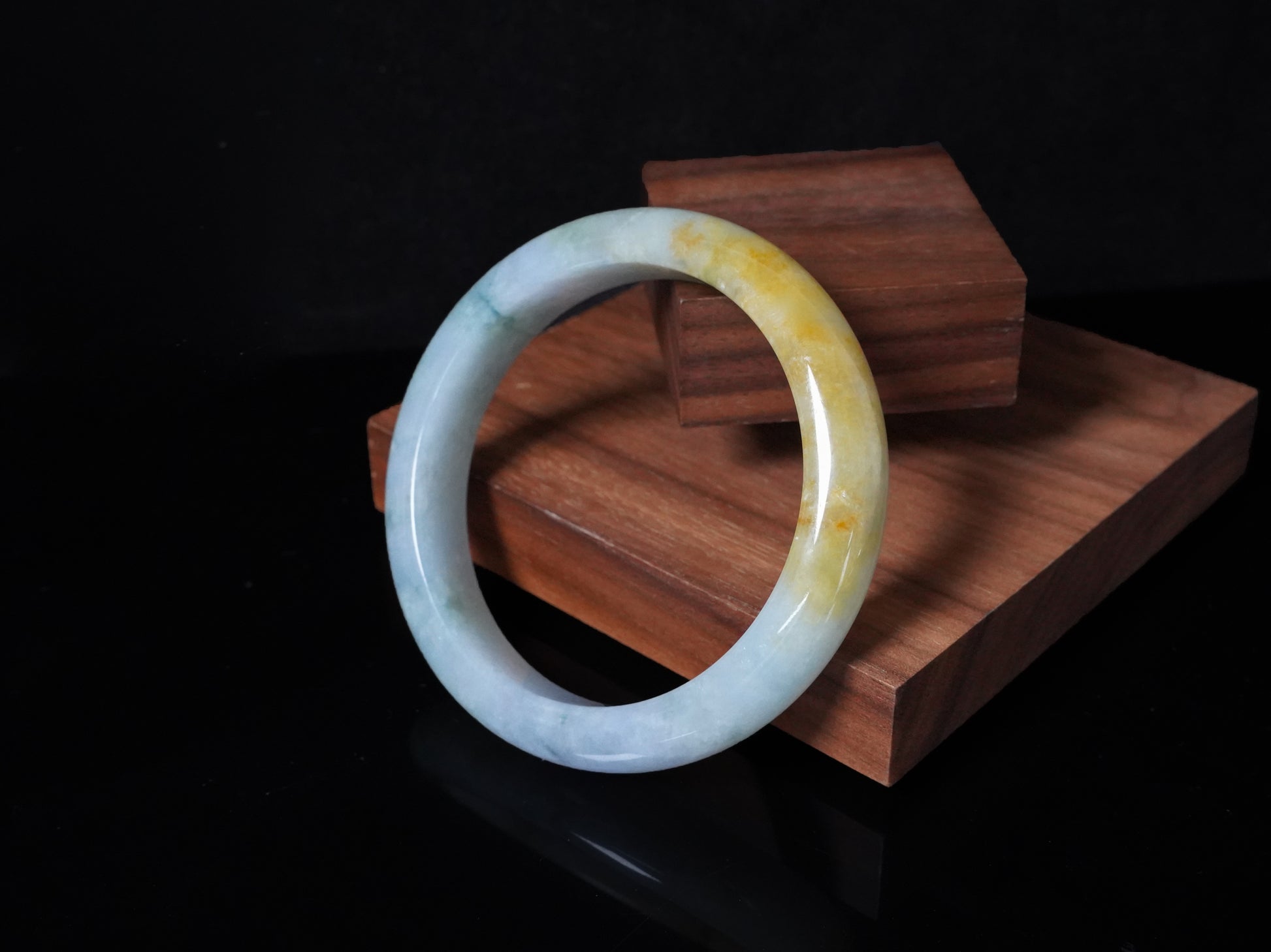 This jadeite bangle has a white base with floating green and honey-yellow hues.