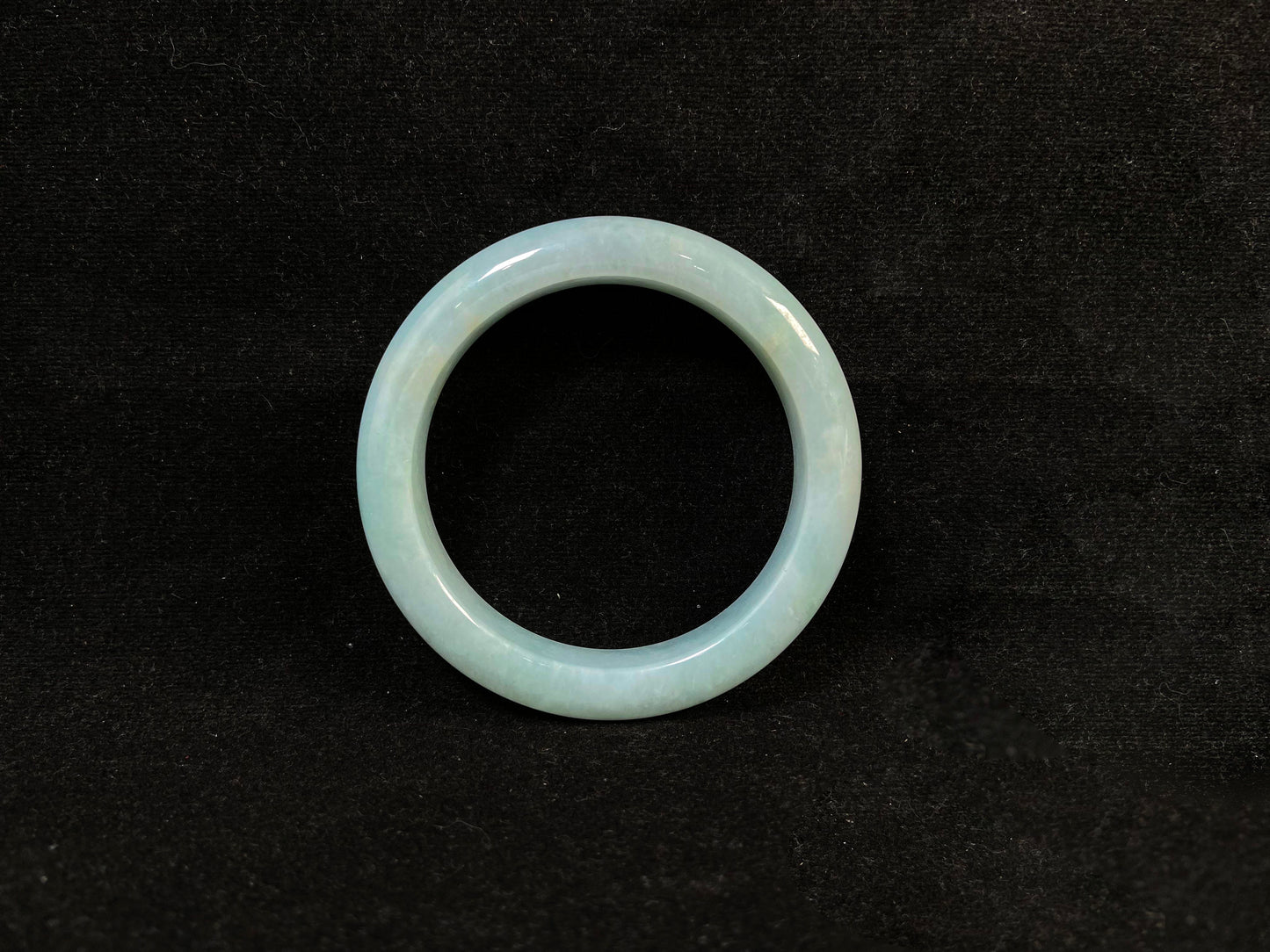 This bracelet showcases a pale green jade with a subtle purple hue.