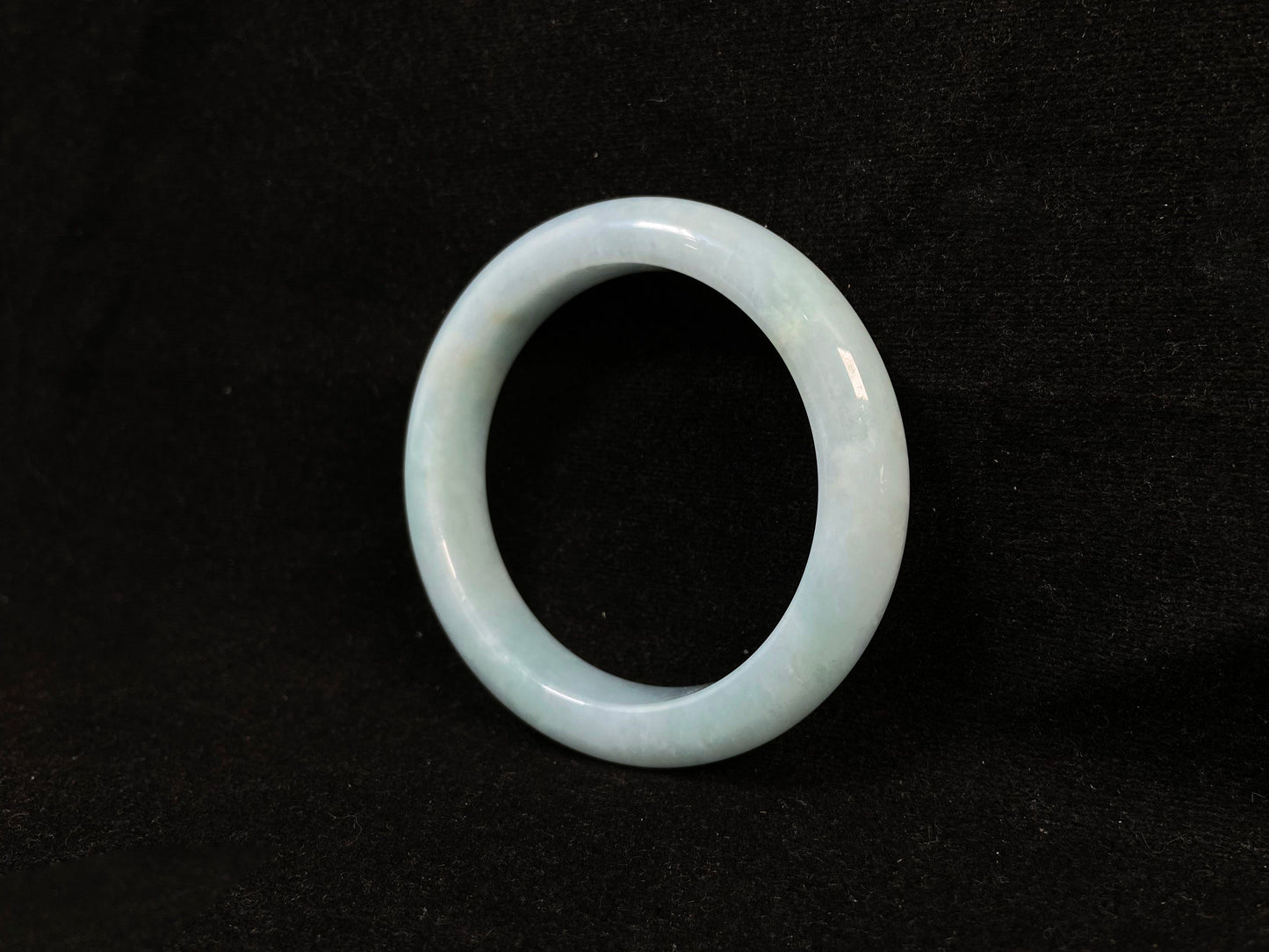 This bracelet showcases a pale green jade with a subtle purple hue.