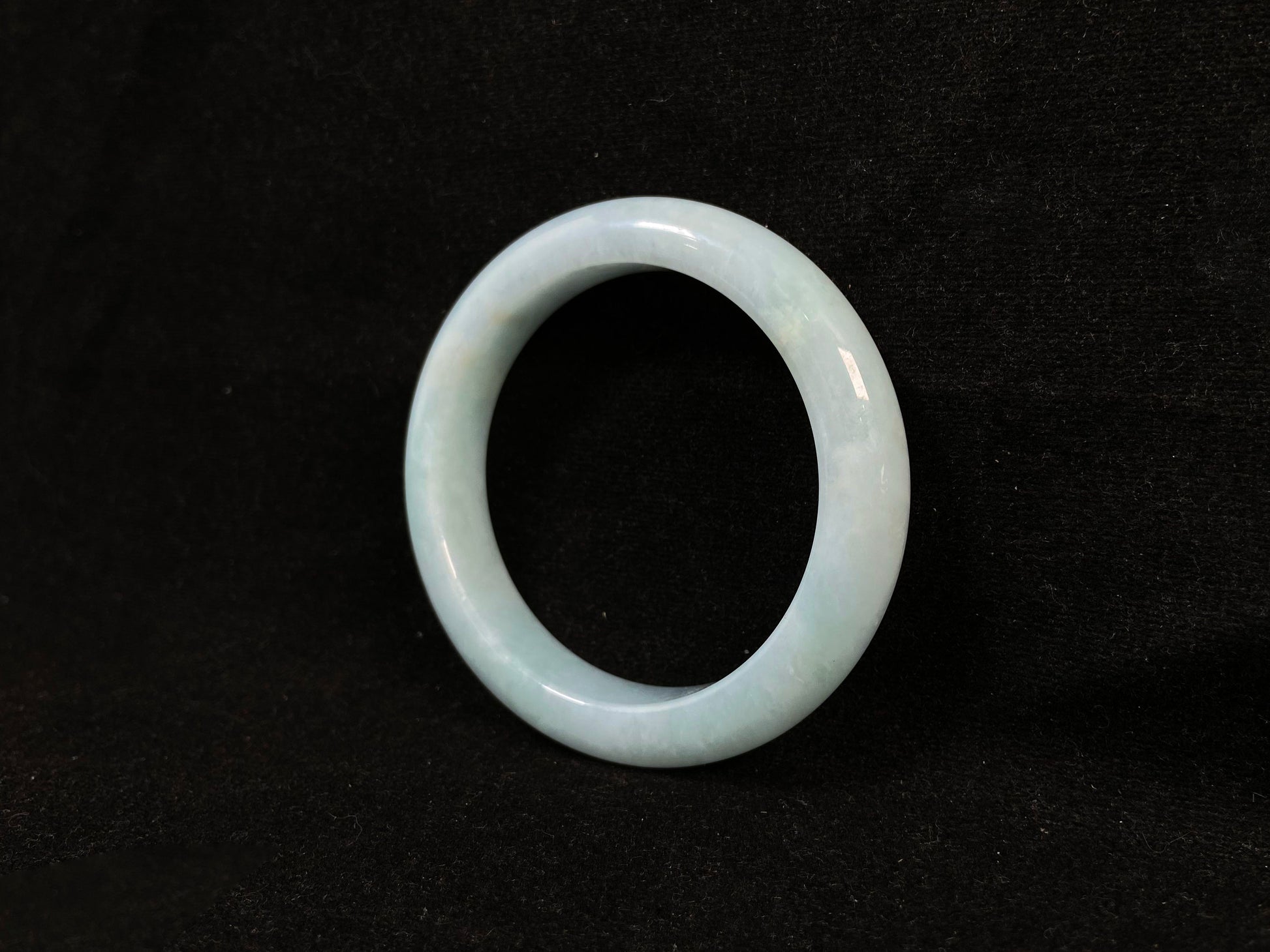 This bracelet showcases a pale green jade with a subtle purple hue.