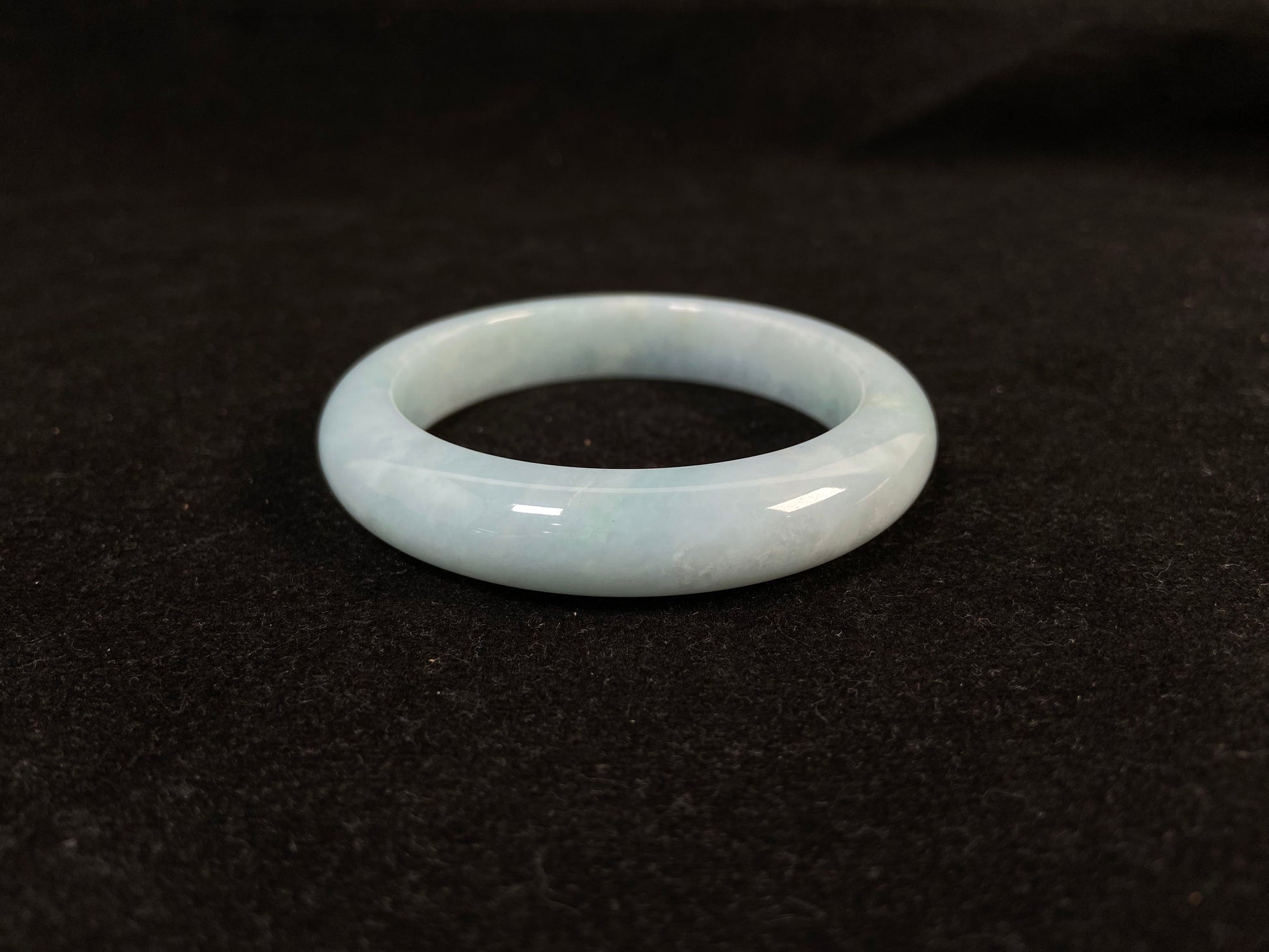 This bracelet showcases a pale green jade with a subtle purple hue.