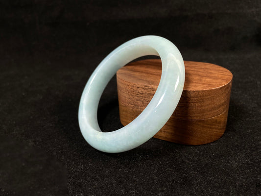 This bracelet showcases a pale green jade with a subtle purple hue.